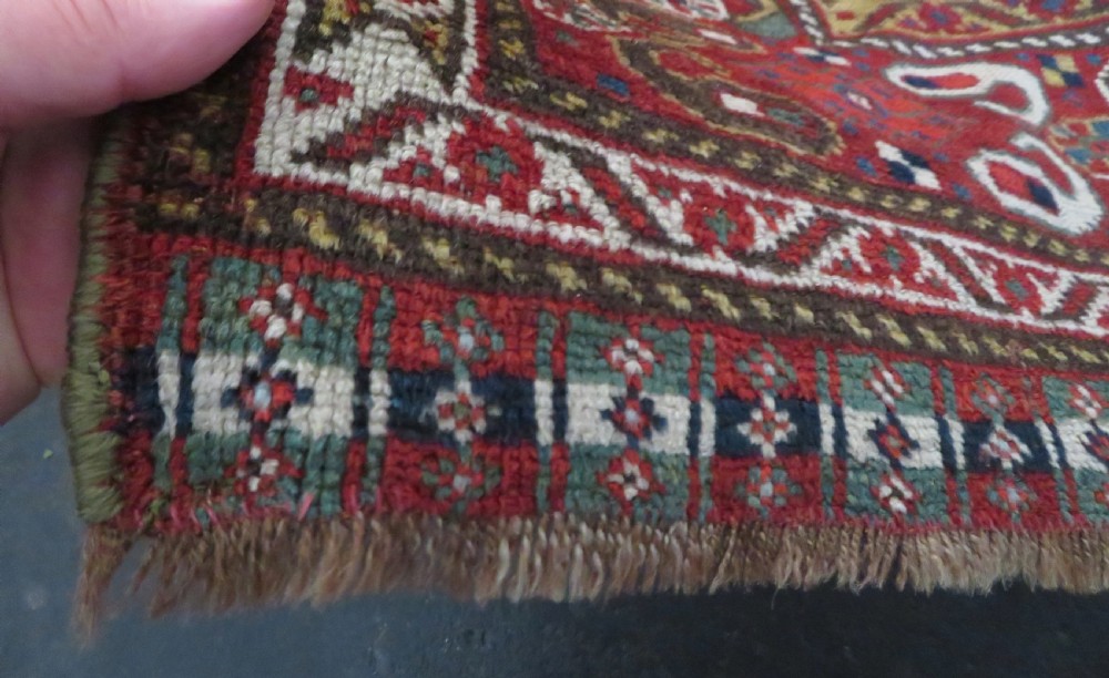 An antique hand-woven Persian Khamseh wool rug featuring a central geometric medallion with tribal bird motifs in red, navy blue, and ivory tones. View VII