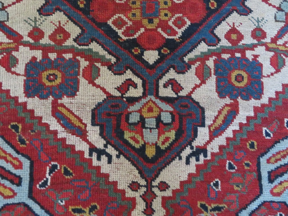 An antique hand-woven Persian Khamseh wool rug featuring a central geometric medallion with tribal bird motifs in red, navy blue, and ivory tones. View VIII