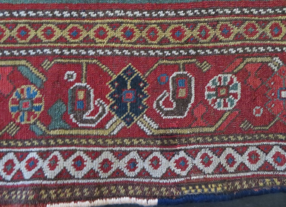 An antique hand-woven Persian Khamseh wool rug featuring a central geometric medallion with tribal bird motifs in red, navy blue, and ivory tones. View XIII