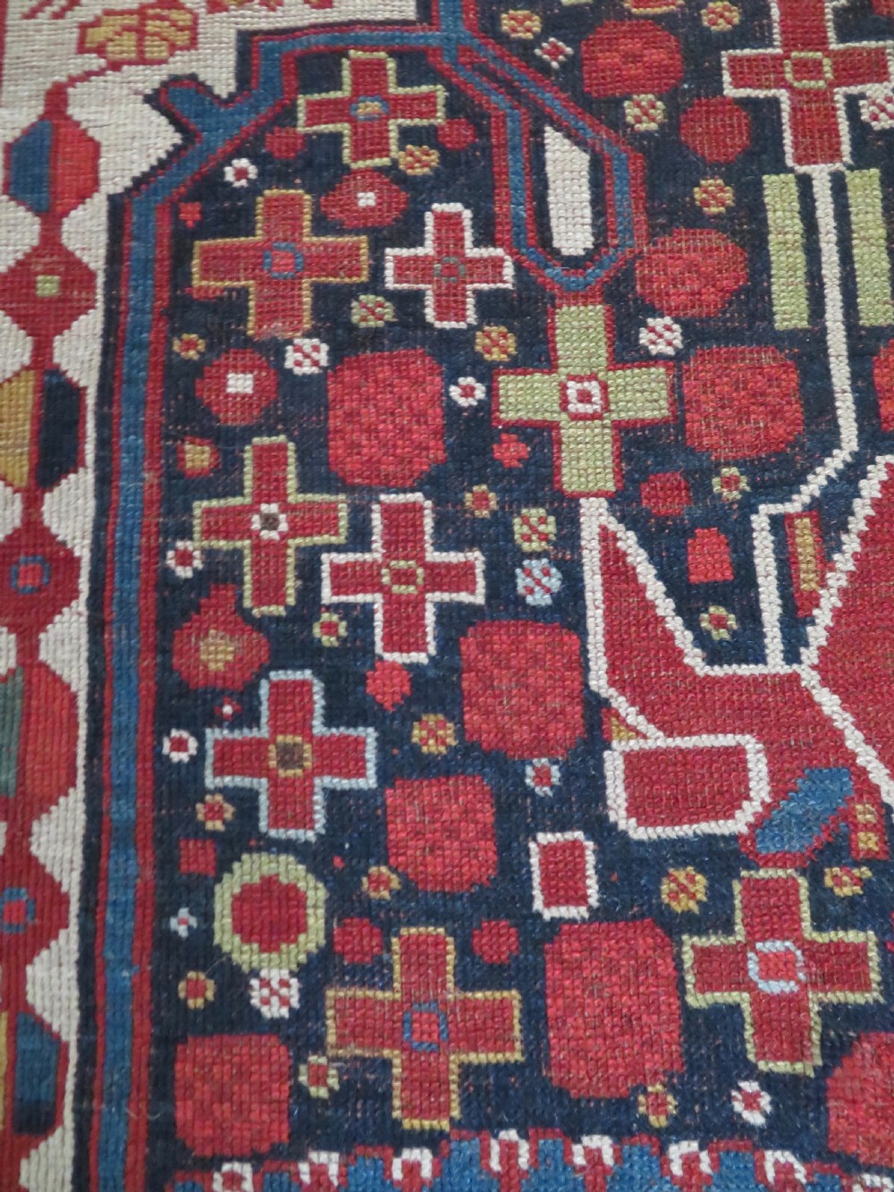 An antique hand-woven Persian Khamseh wool rug featuring a central geometric medallion with tribal bird motifs in red, navy blue, and ivory tones. View XIX