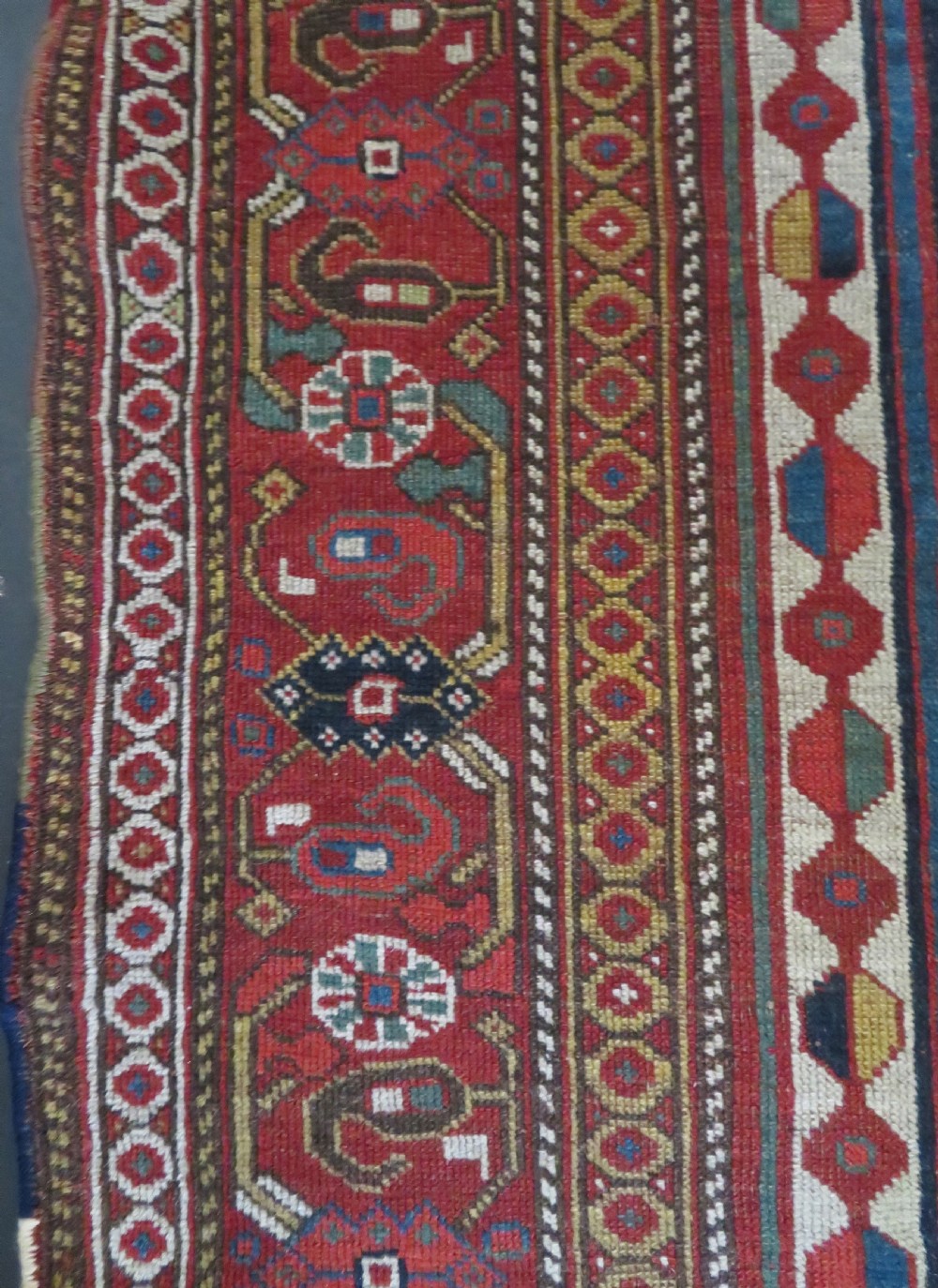 An antique hand-woven Persian Khamseh wool rug featuring a central geometric medallion with tribal bird motifs in red, navy blue, and ivory tones. View XX