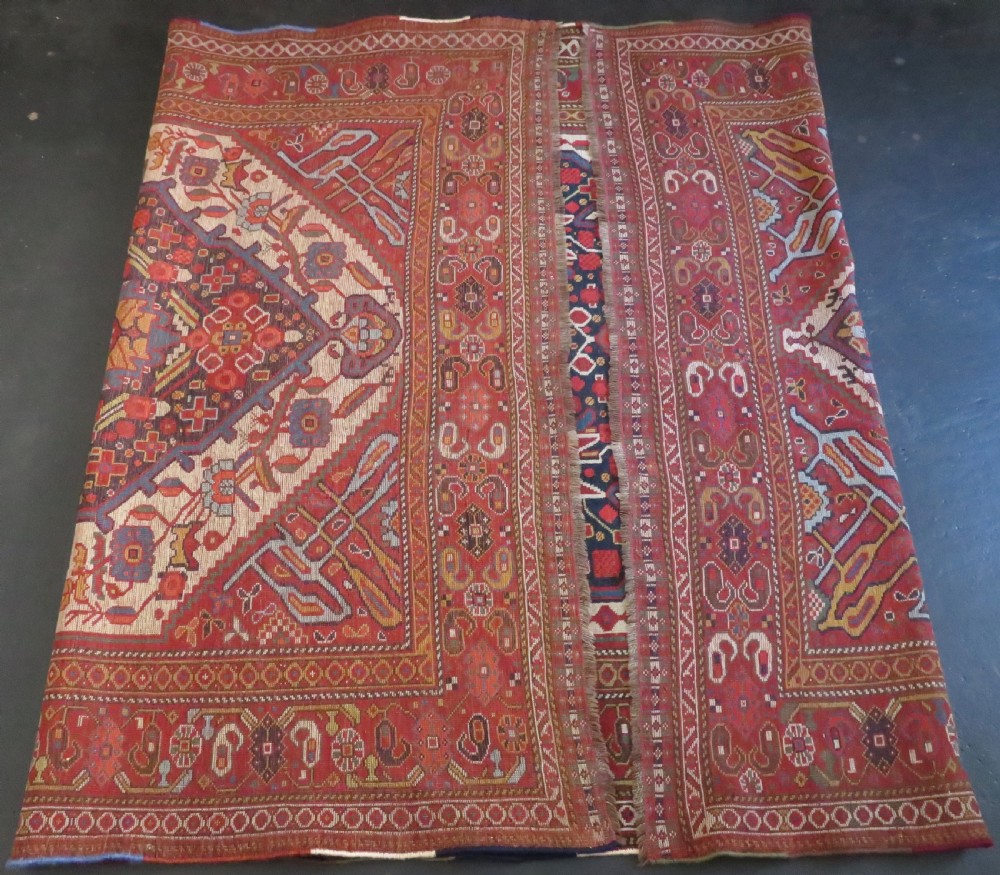 An antique hand-woven Persian Khamseh wool rug featuring a central geometric medallion with tribal bird motifs in red, navy blue, and ivory tones. View XXI