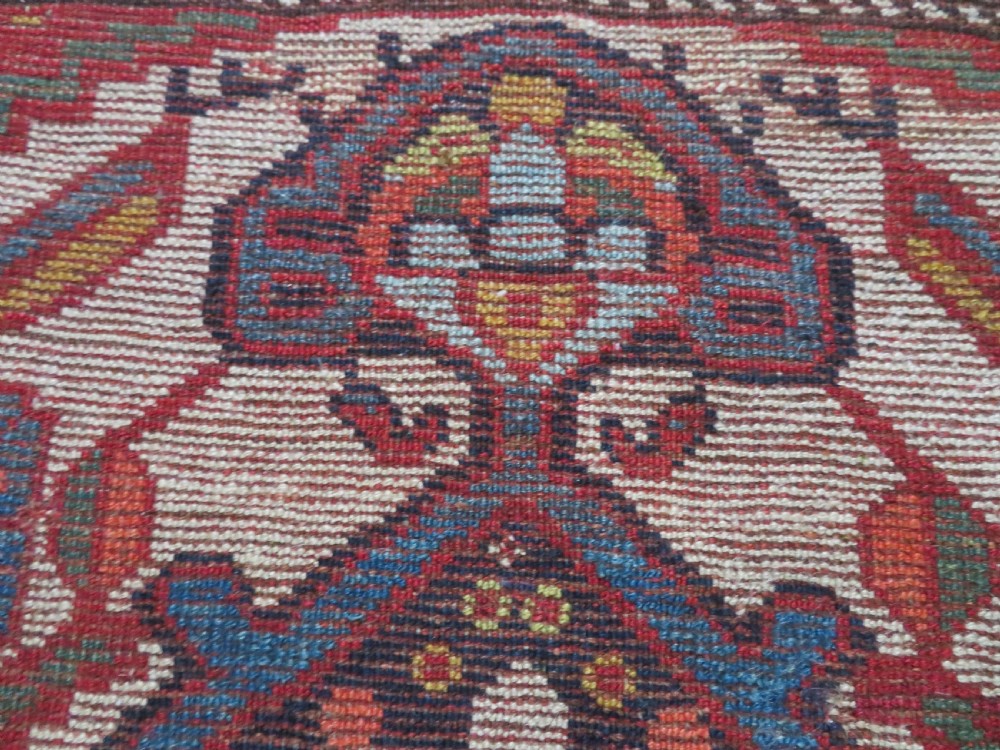 An antique hand-woven Persian Khamseh wool rug featuring a central geometric medallion with tribal bird motifs in red, navy blue, and ivory tones. View XXIII