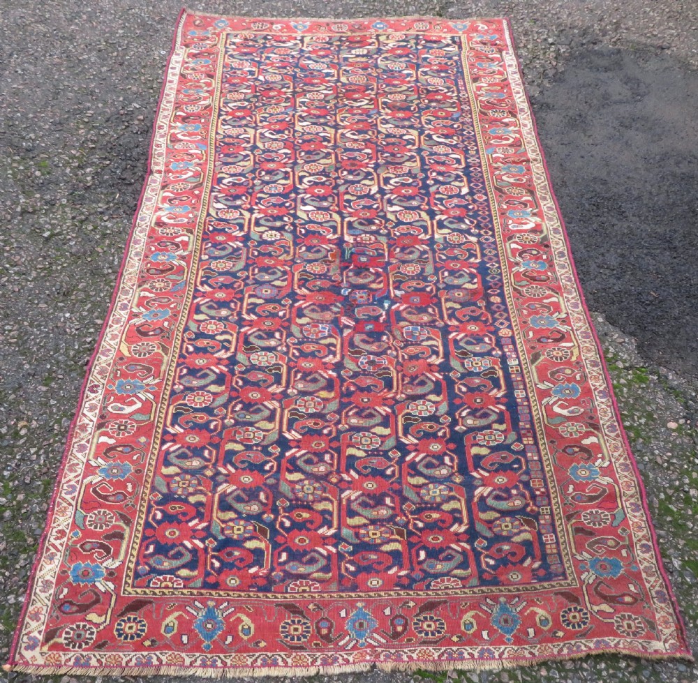 A long hand-knotted Persian Khamseh rug with a navy blue field filled with repeating floral and boteh motifs, framed by a patterned red border. View II