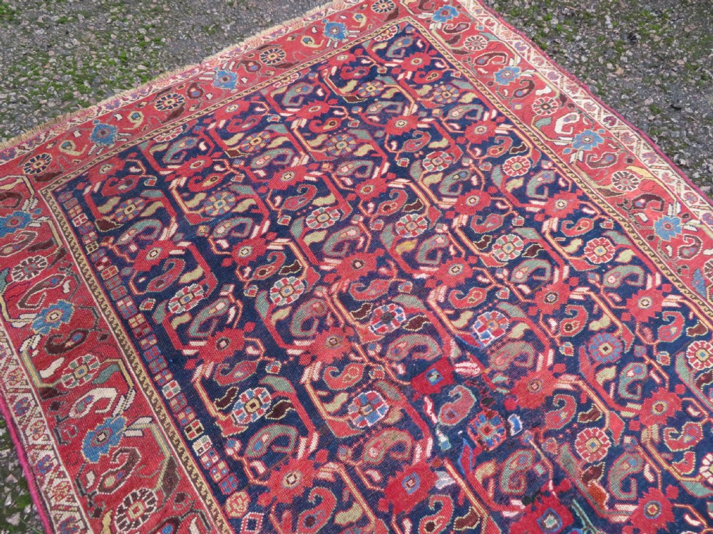 A long hand-knotted Persian Khamseh rug with a navy blue field filled with repeating floral and boteh motifs, framed by a patterned red border. View IV