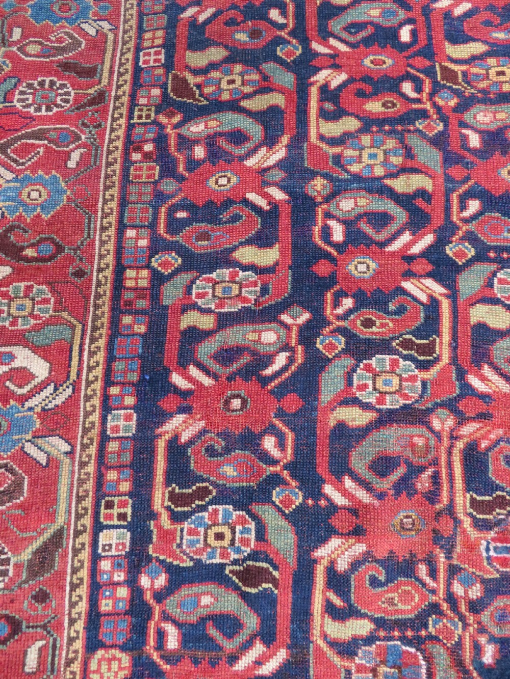A long hand-knotted Persian Khamseh rug with a navy blue field filled with repeating floral and boteh motifs, framed by a patterned red border. View X