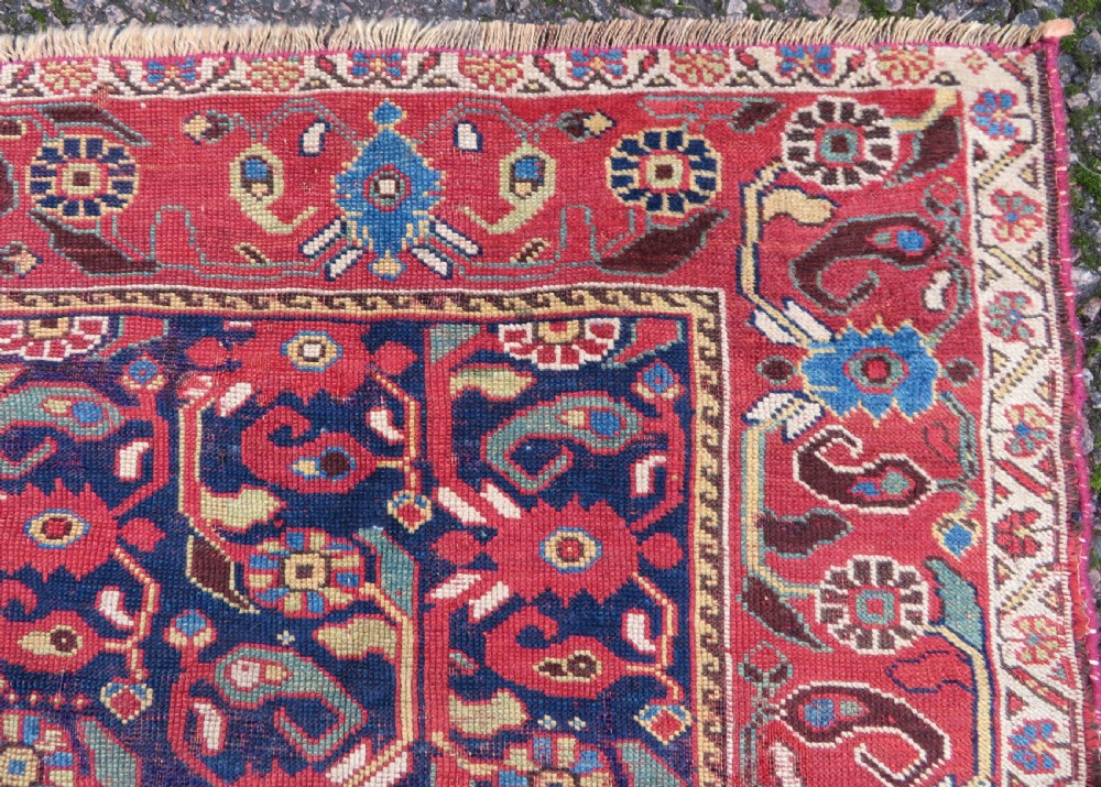 A long hand-knotted Persian Khamseh rug with a navy blue field filled with repeating floral and boteh motifs, framed by a patterned red border. View XII
