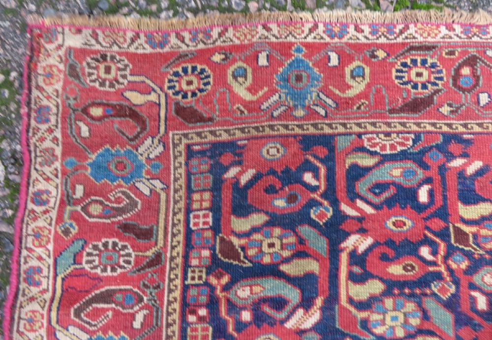 A long hand-knotted Persian Khamseh rug with a navy blue field filled with repeating floral and boteh motifs, framed by a patterned red border. View XIII