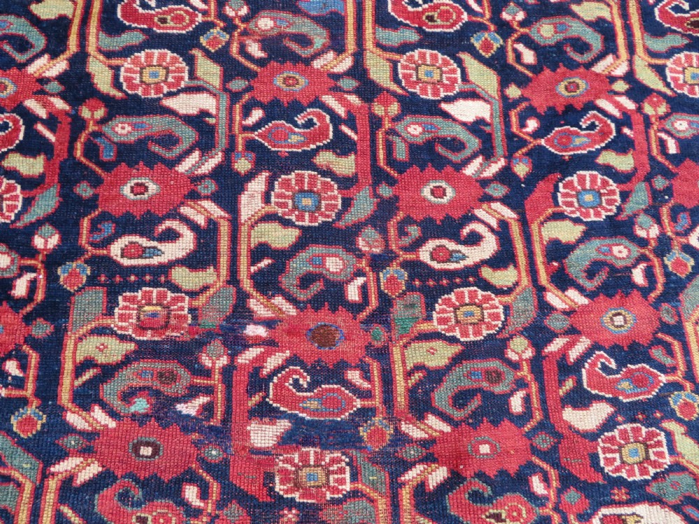A long hand-knotted Persian Khamseh rug with a navy blue field filled with repeating floral and boteh motifs, framed by a patterned red border. View XIV