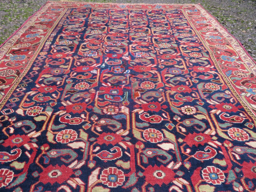 A long hand-knotted Persian Khamseh rug with a navy blue field filled with repeating floral and boteh motifs, framed by a patterned red border. View XV
