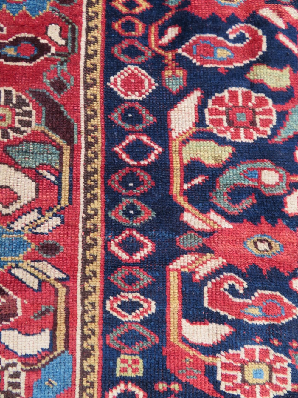 A long hand-knotted Persian Khamseh rug with a navy blue field filled with repeating floral and boteh motifs, framed by a patterned red border. View XVII
