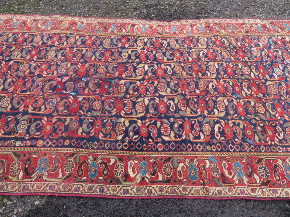 A long hand-knotted Persian Khamseh rug with a navy blue field filled with repeating floral and boteh motifs, framed by a patterned red border. View XIX