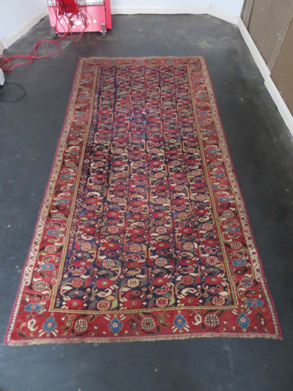 A long hand-knotted Persian Khamseh rug with a navy blue field filled with repeating floral and boteh motifs, framed by a patterned red border. View XXIV