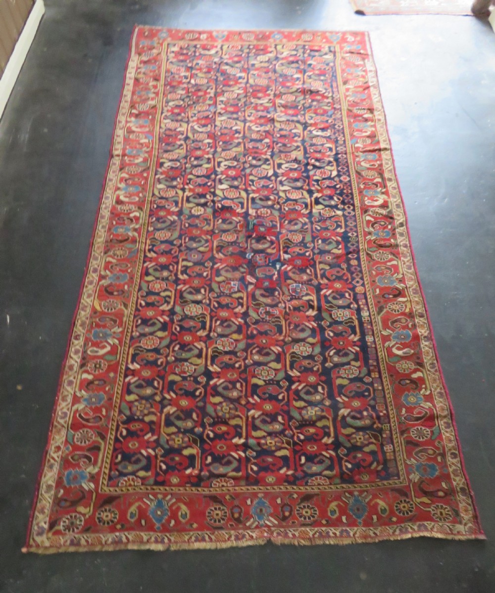 A long hand-knotted Persian Khamseh rug with a navy blue field filled with repeating floral and boteh motifs, framed by a patterned red border. View XXV