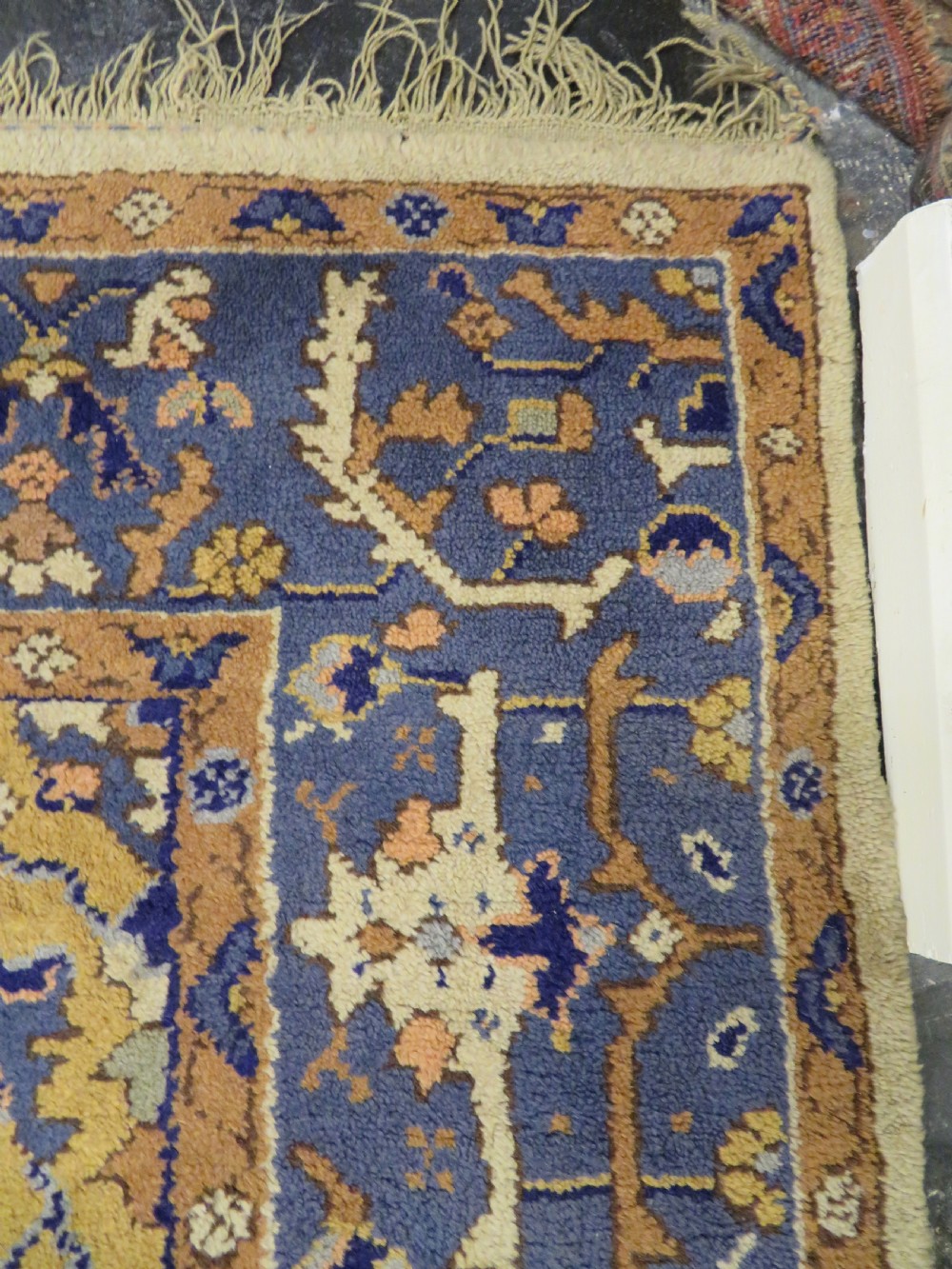 An antique hand-knotted wool area carpet featuring an ivory central field, detailed central medallion, corner spandrels, and a broad indigo floral border. View VIII