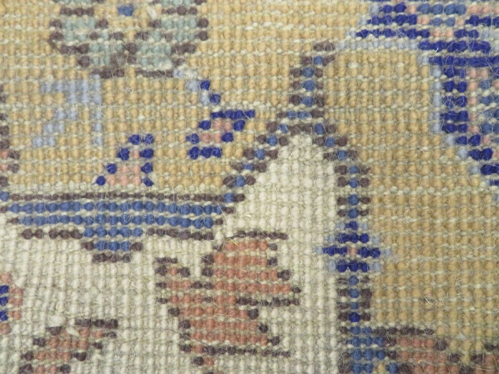 An antique hand-knotted wool area carpet featuring an ivory central field, detailed central medallion, corner spandrels, and a broad indigo floral border. View XXVIII