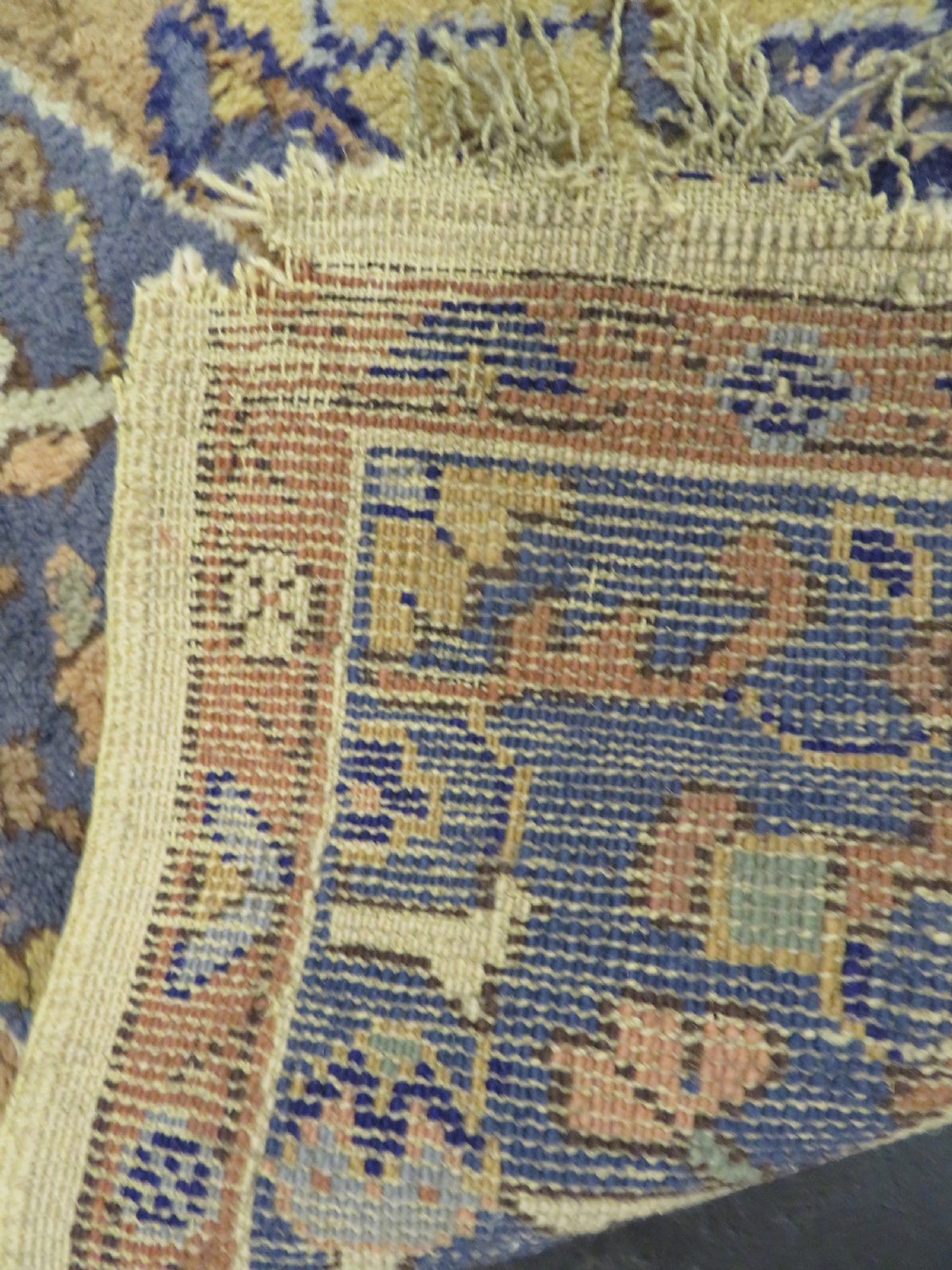 An antique hand-knotted wool area carpet featuring an ivory central field, detailed central medallion, corner spandrels, and a broad indigo floral border. View XXX