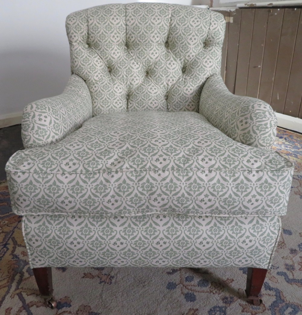 A side profile of a Bridgewater armchair upholstered in green and off-white patterned fabric with dark wooden legs and brass castors. View II