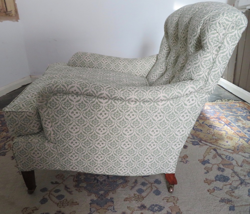 A side profile of a Bridgewater armchair upholstered in green and off-white patterned fabric with dark wooden legs and brass castors. View XI