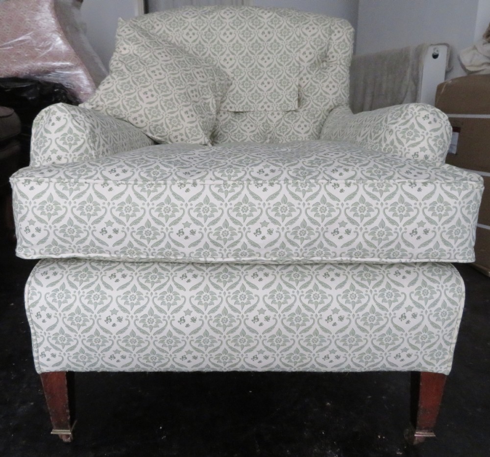 A side profile of a Bridgewater armchair upholstered in green and off-white patterned fabric with dark wooden legs and brass castors. View XVIII