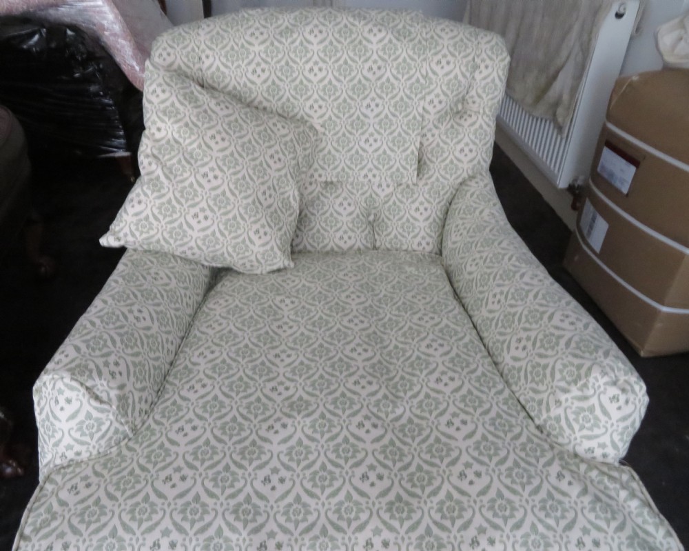 A side profile of a Bridgewater armchair upholstered in green and off-white patterned fabric with dark wooden legs and brass castors. View XIX