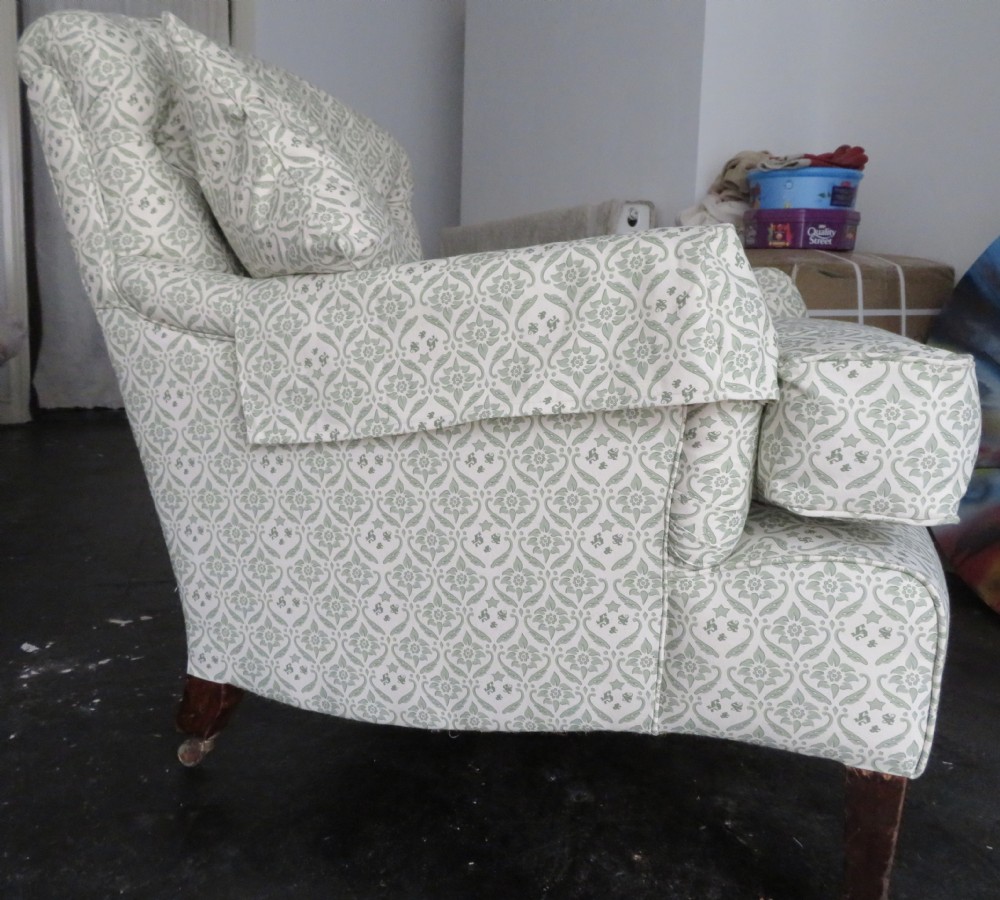 A side profile of a Bridgewater armchair upholstered in green and off-white patterned fabric with dark wooden legs and brass castors. View XX