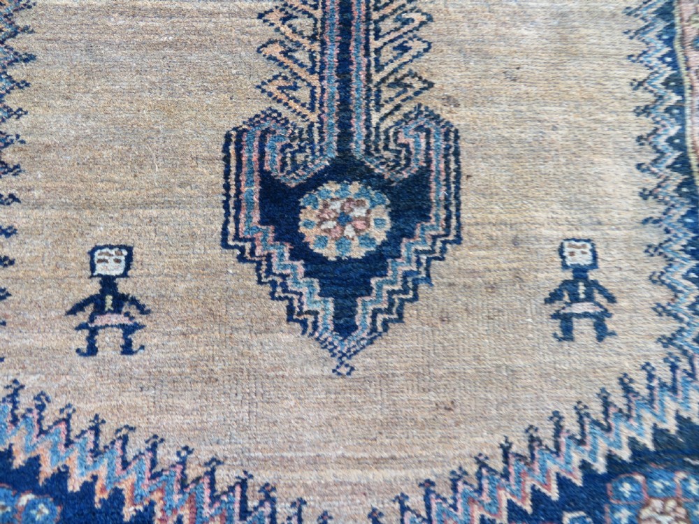 A long, narrow hand-knotted antique Persian Kurdish wool runner rug with geometric central column motifs on a camel field bordered in dark navy blue. View VI
