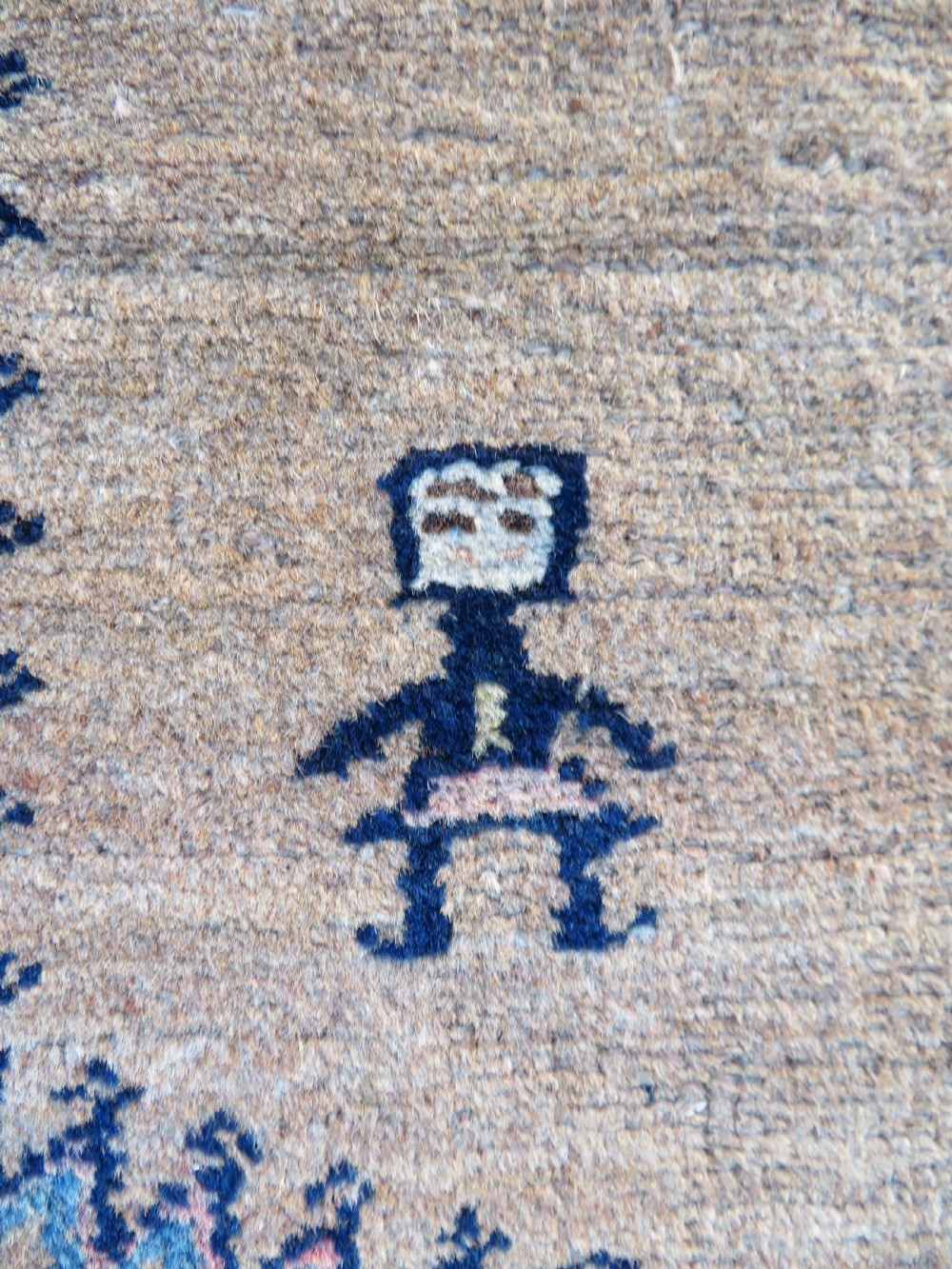 A long, narrow hand-knotted antique Persian Kurdish wool runner rug with geometric central column motifs on a camel field bordered in dark navy blue. View IX