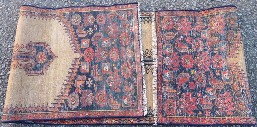 A long, narrow hand-knotted antique Persian Kurdish wool runner rug with geometric central column motifs on a camel field bordered in dark navy blue. View XIII