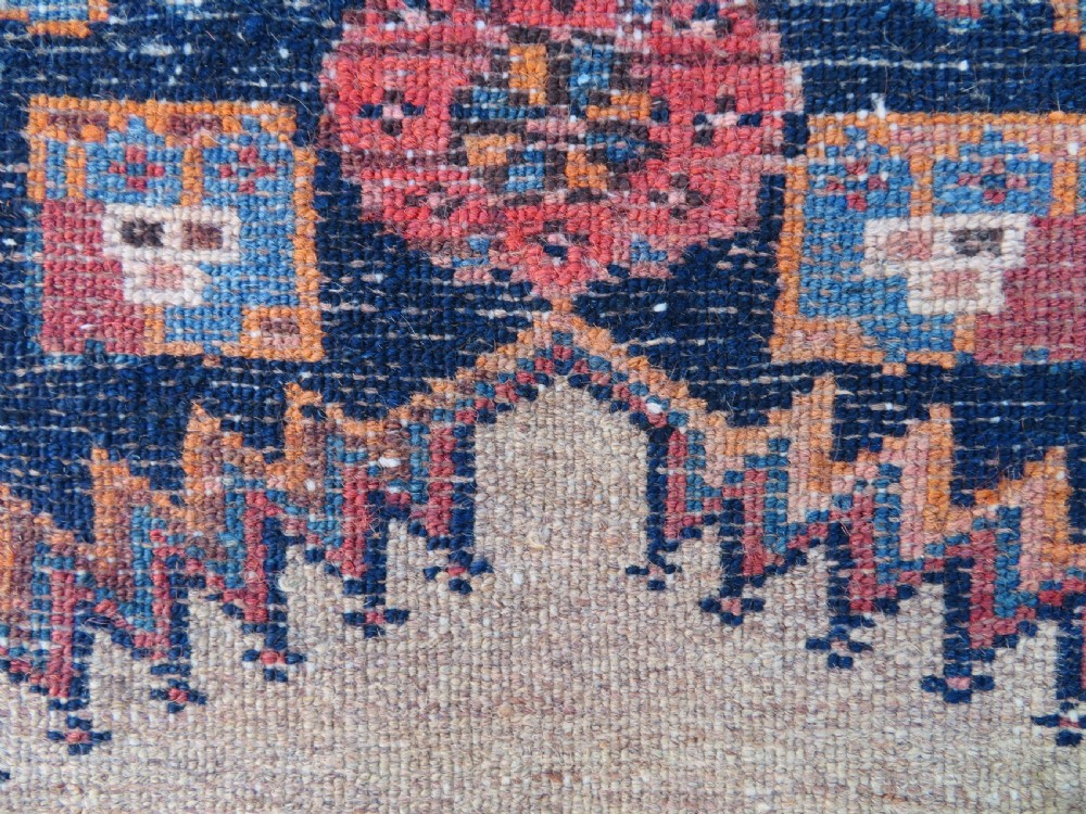A long, narrow hand-knotted antique Persian Kurdish wool runner rug with geometric central column motifs on a camel field bordered in dark navy blue. View XVI