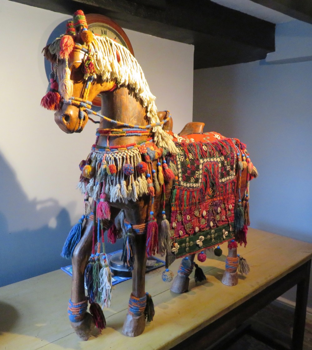 A large carved hardwood model of a standing horse decorated with detailed woven textiles, tassels, and cowrie shells. View II