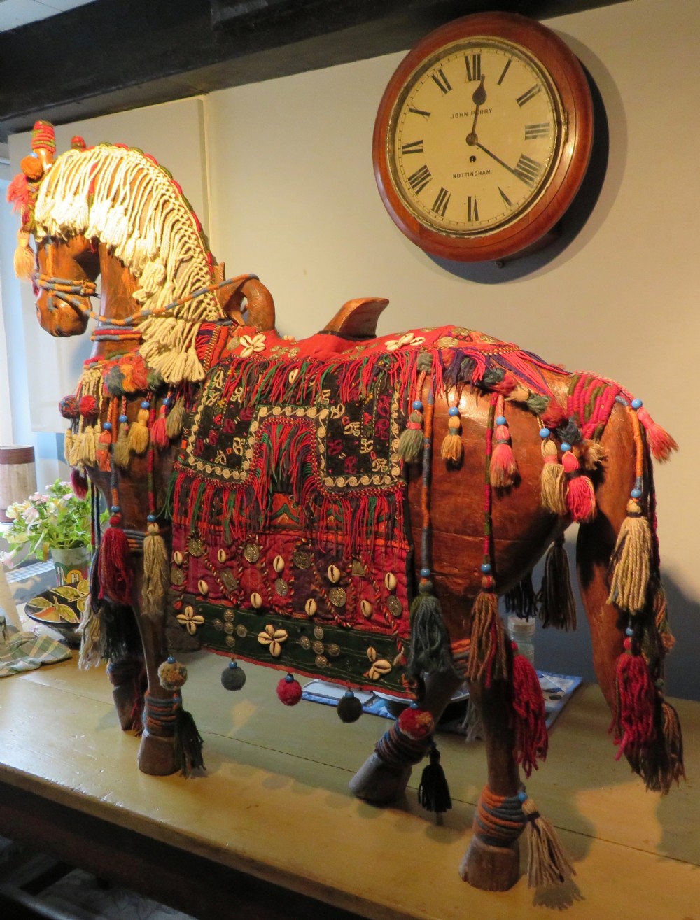 A large carved hardwood model of a standing horse decorated with detailed woven textiles, tassels, and cowrie shells. View III