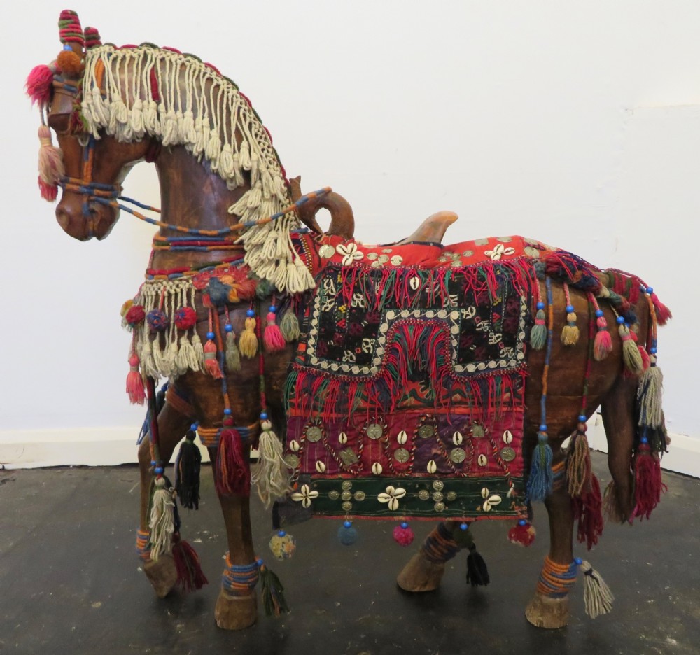A large carved hardwood model of a standing horse decorated with detailed woven textiles, tassels, and cowrie shells. View V