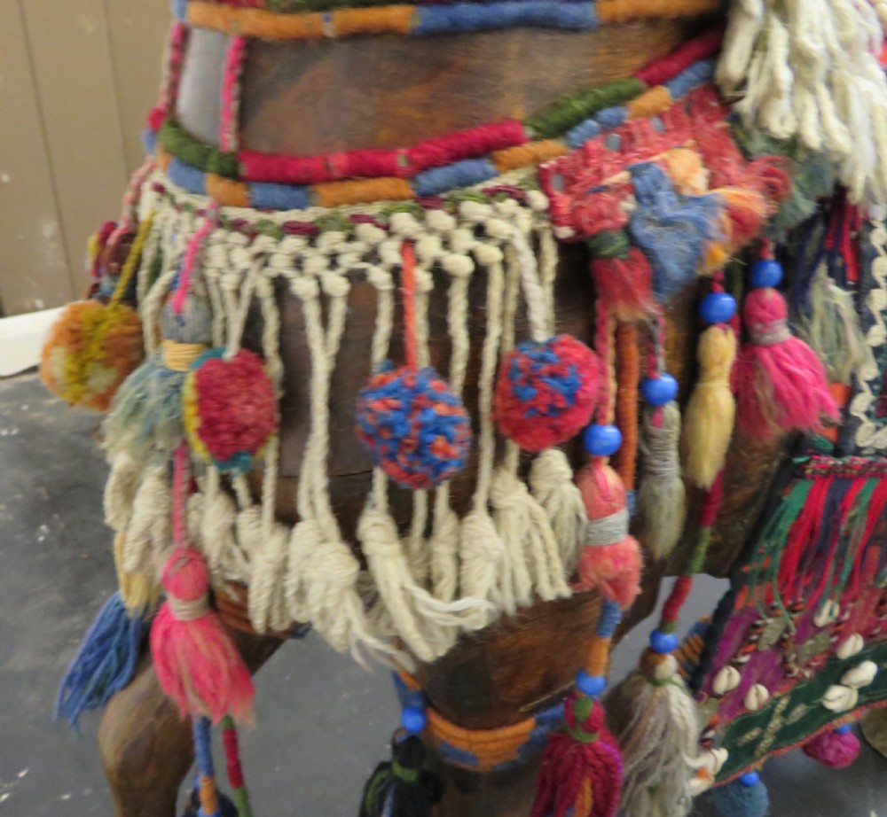 A large carved hardwood model of a standing horse decorated with detailed woven textiles, tassels, and cowrie shells. View XI