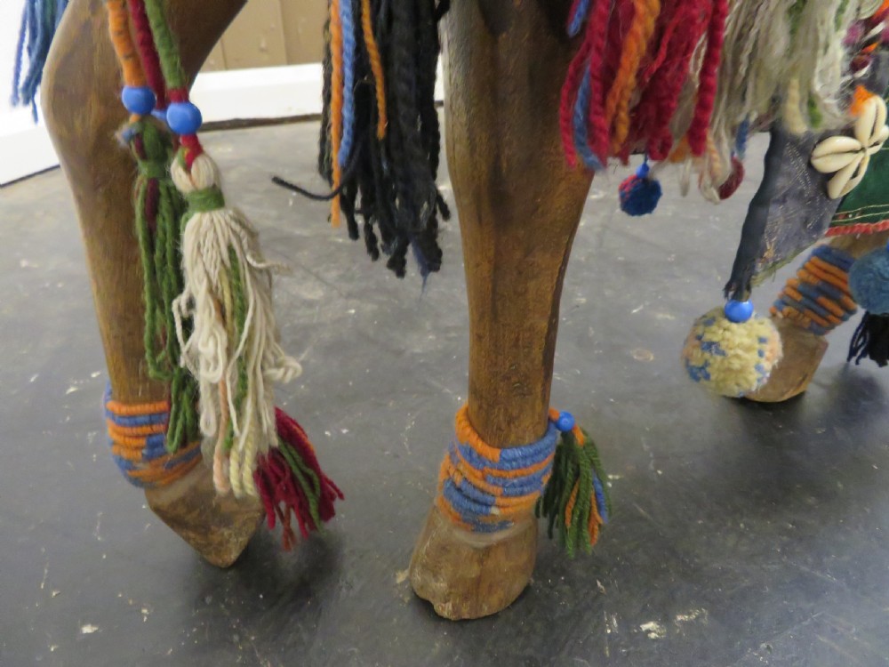 A large carved hardwood model of a standing horse decorated with detailed woven textiles, tassels, and cowrie shells. View XII