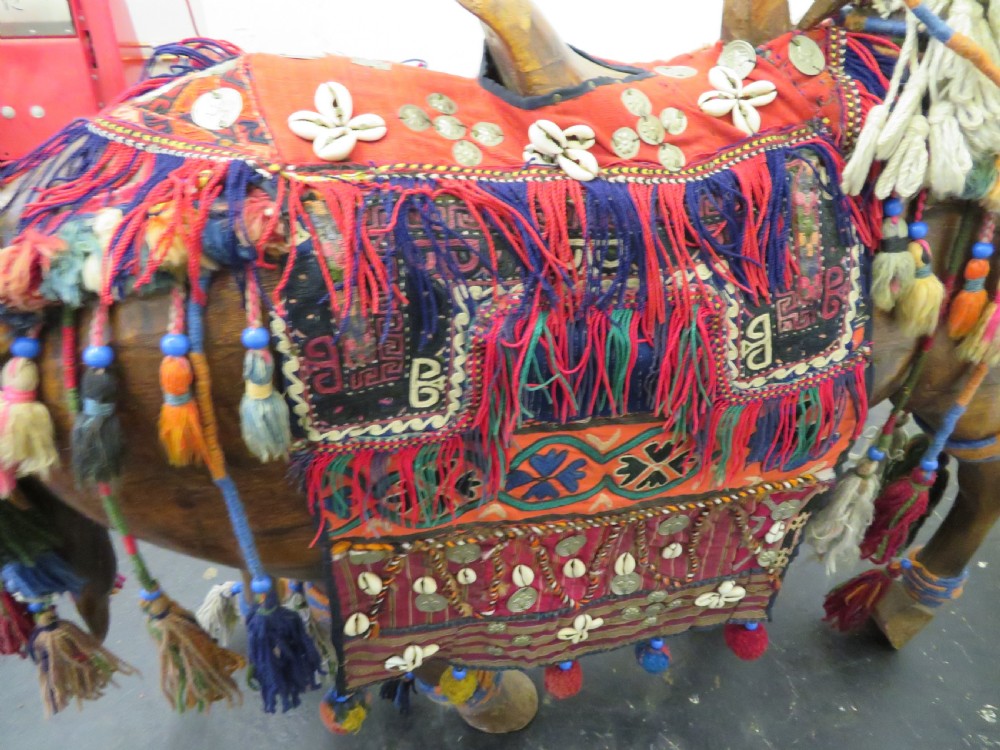 A large carved hardwood model of a standing horse decorated with detailed woven textiles, tassels, and cowrie shells. View XVI