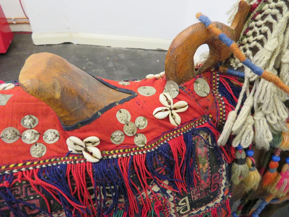 A large carved hardwood model of a standing horse decorated with detailed woven textiles, tassels, and cowrie shells. View XIX