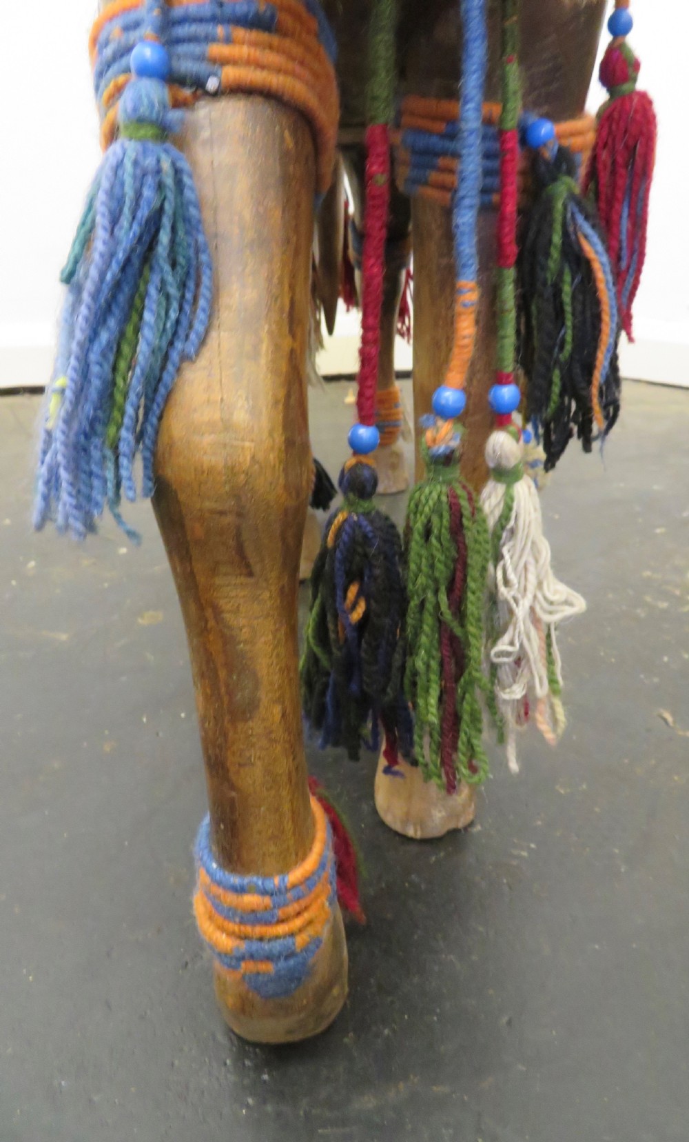 A large carved hardwood model of a standing horse decorated with detailed woven textiles, tassels, and cowrie shells. View XXII