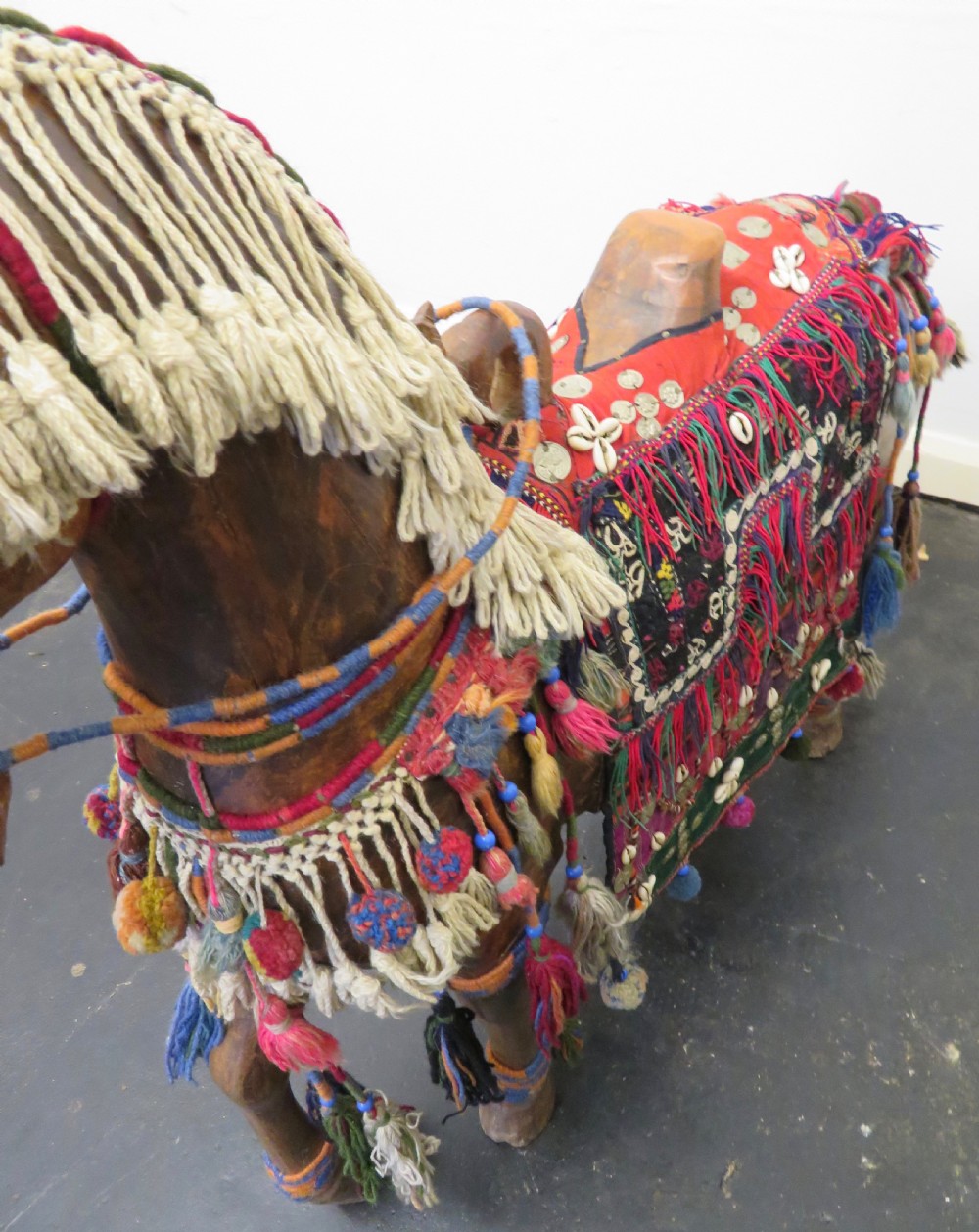 A large carved hardwood model of a standing horse decorated with detailed woven textiles, tassels, and cowrie shells. View XXIII