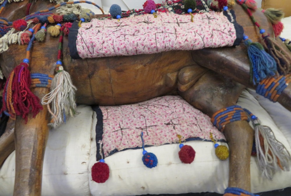 A large carved hardwood model of a standing horse decorated with detailed woven textiles, tassels, and cowrie shells. View XXVI