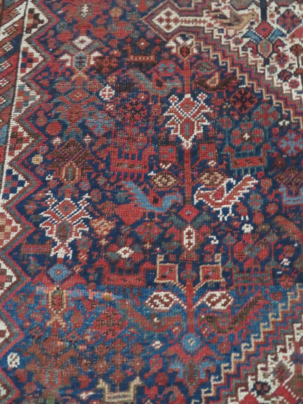 An antique hand-knotted Persian Khamseh rug featuring three diamond central medallions and bird motifs in deep red, navy, cream, and terracotta tones. View VIII