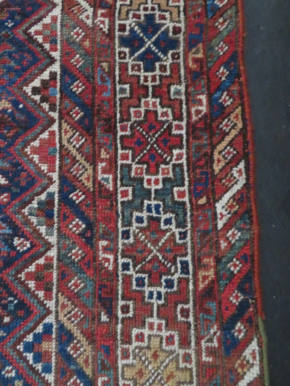 An antique hand-knotted Persian Khamseh rug featuring three diamond central medallions and bird motifs in deep red, navy, cream, and terracotta tones. View X