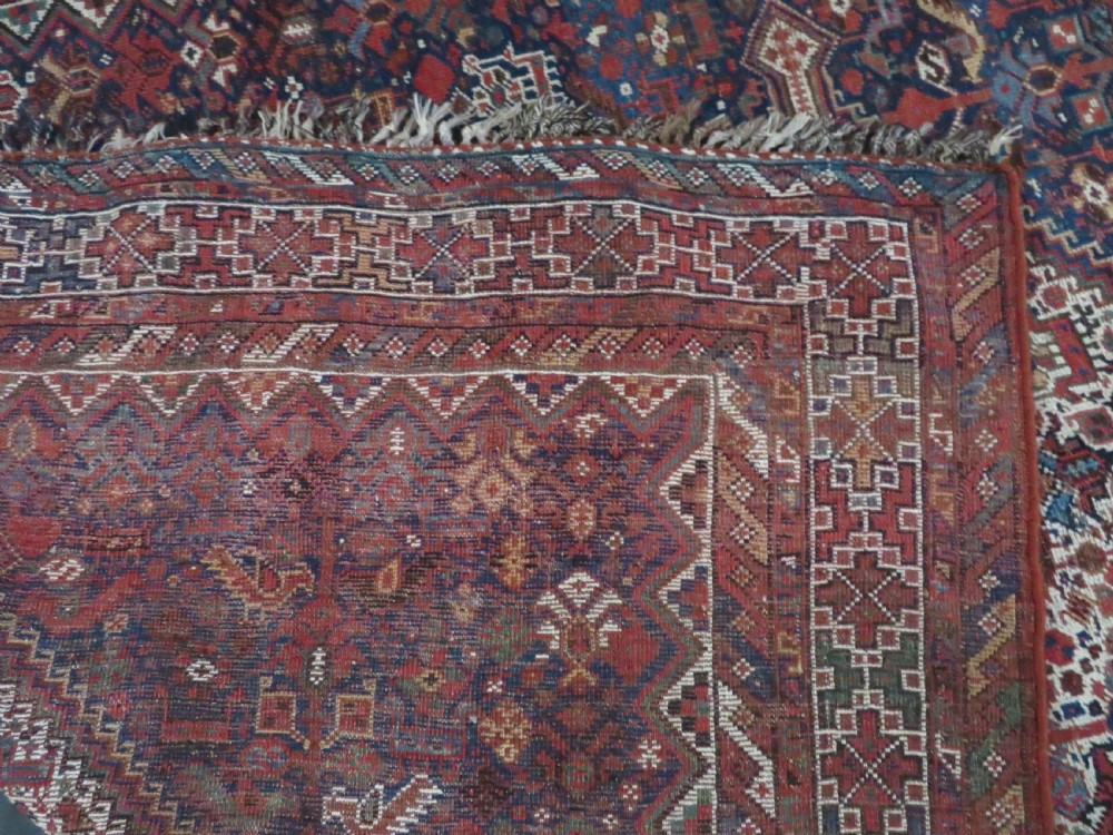 An antique hand-knotted Persian Khamseh rug featuring three diamond central medallions and bird motifs in deep red, navy, cream, and terracotta tones. View XV