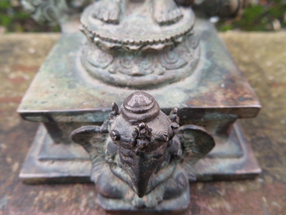 An ancient cast metal figure of Vishnu standing within a flame-edged aureole on a lotus base above a small figure. View VI
