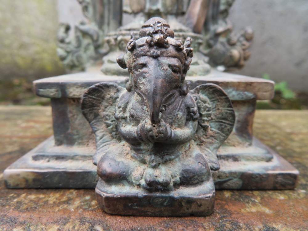 An ancient cast metal figure of Vishnu standing within a flame-edged aureole on a lotus base above a small figure. View VII