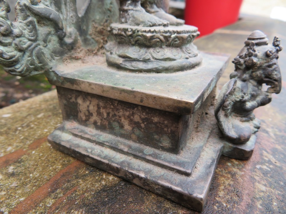 An ancient cast metal figure of Vishnu standing within a flame-edged aureole on a lotus base above a small figure. View VIII