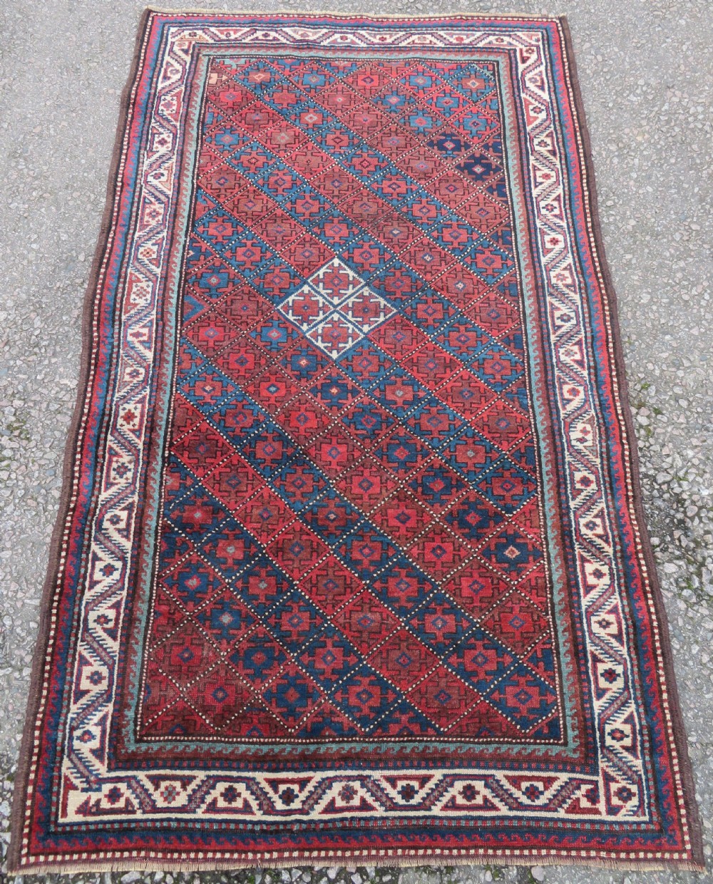 An antique hand-knotted Quchan Kurdish wool rug displaying a central diamond pattern inside a dark red and navy lattice grid with geometric borders. View II