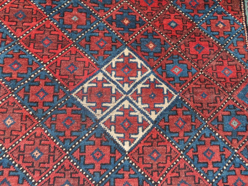 An antique hand-knotted Quchan Kurdish wool rug displaying a central diamond pattern inside a dark red and navy lattice grid with geometric borders. View III