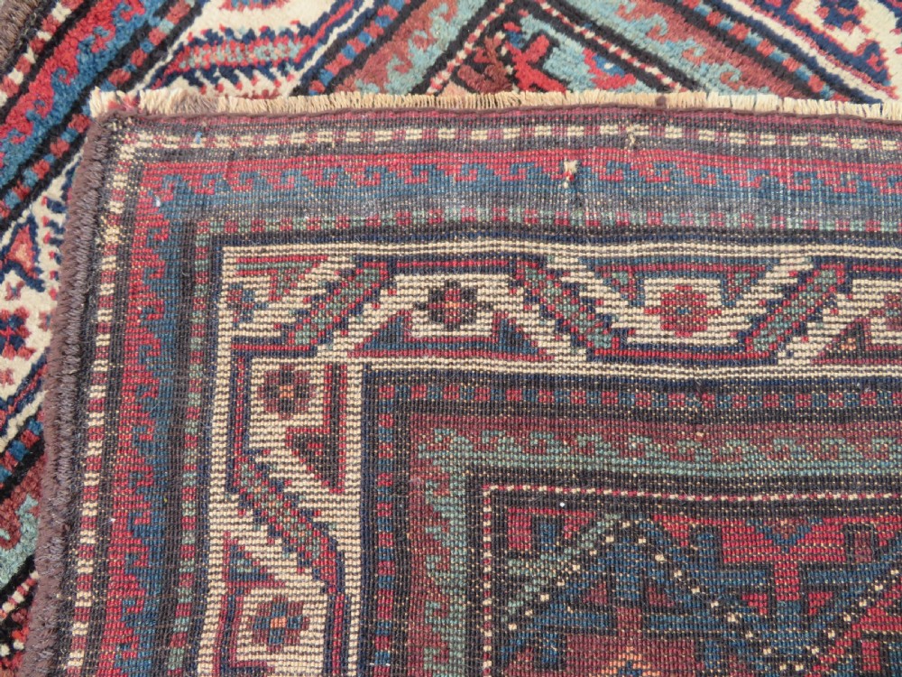 An antique hand-knotted Quchan Kurdish wool rug displaying a central diamond pattern inside a dark red and navy lattice grid with geometric borders. View VII
