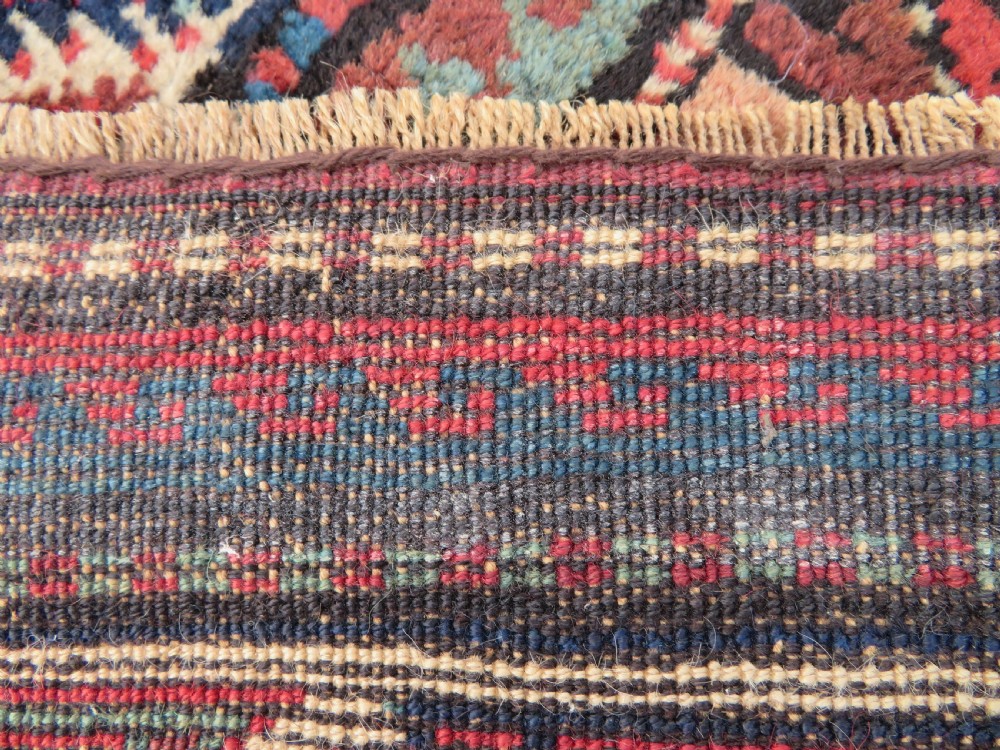 An antique hand-knotted Quchan Kurdish wool rug displaying a central diamond pattern inside a dark red and navy lattice grid with geometric borders. View VIII